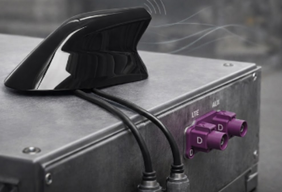Close-up of a shark fin vehicle antenna mounted on a metal enclosure showing purple FAKRA D jacks labeled LTE MAIN and AUX.